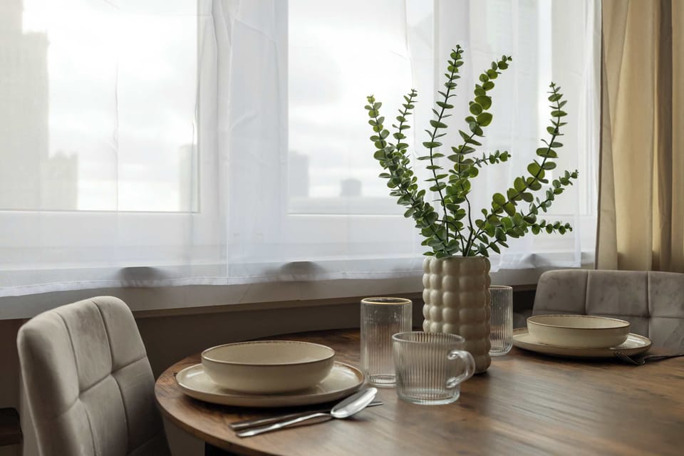 Small dining table with elegant tableware and a vase of fresh flowers.