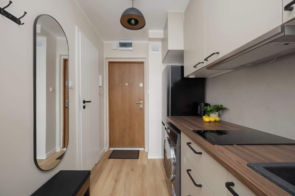 Compact modern kitchen with built-in appliances, light cabinets, and a wooden countertop.
