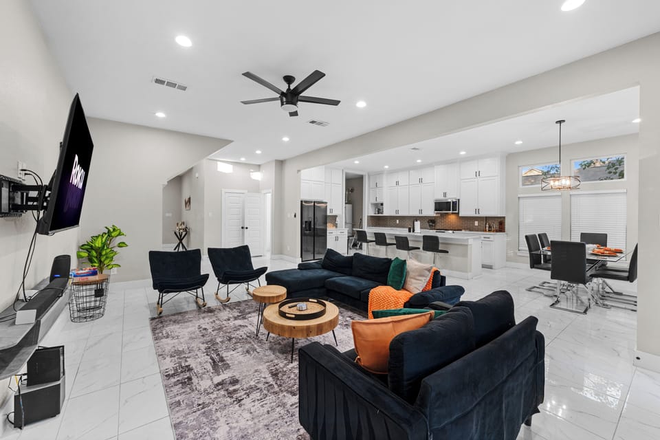 Cozy living room with navy seats, bright pillows, wood tables, and Roku TV.
