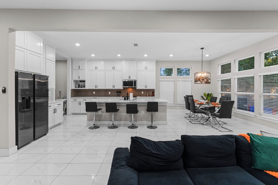 Modern kitchen with white cabinets, big island, bar seating, and natural light.