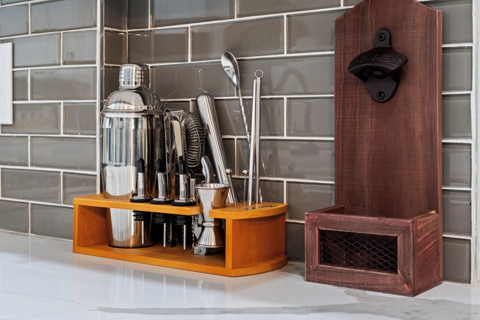Sleek bar setup with shaker, bar tools, and wall-mounted bottle opener.