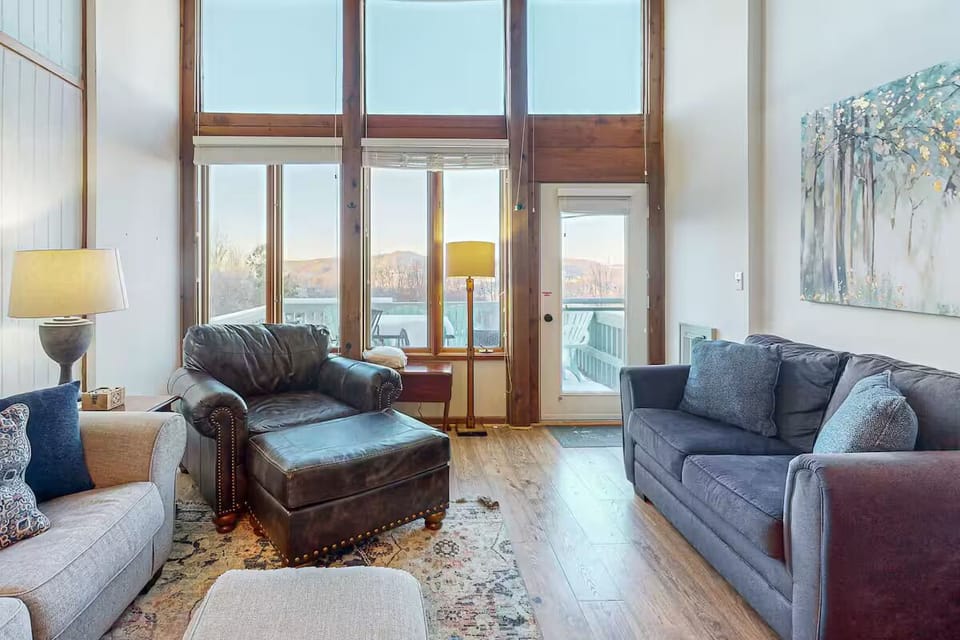Sun-drenched living room with soaring windows and stunning mountain views.