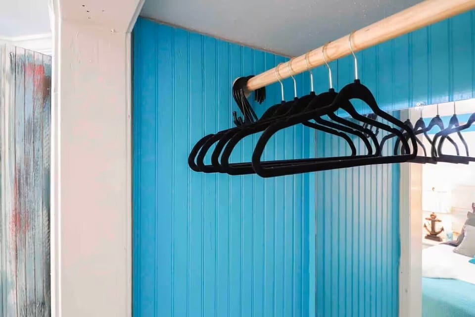 Open closet space with hanging rack and coastal accent wall

