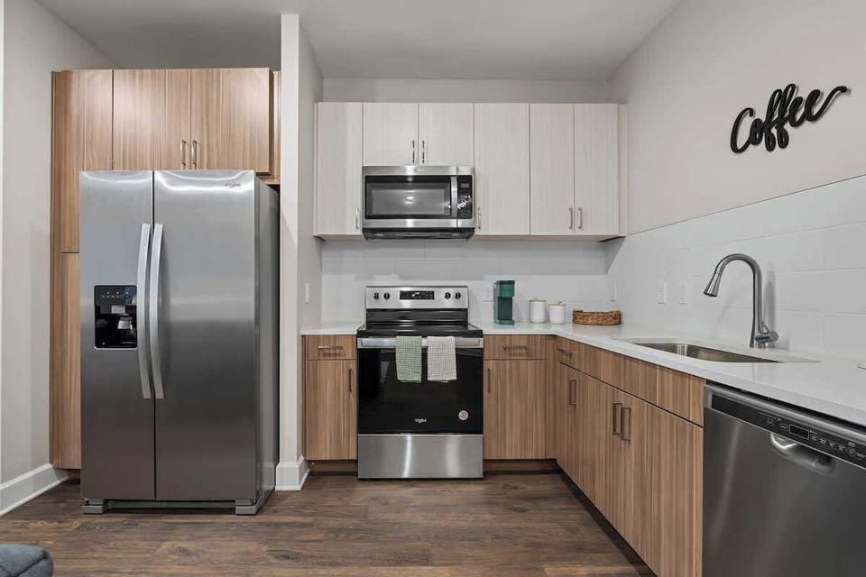 - Sleek kitchen with stainless appliances, wood cabinets, and spacious counters
- Fully equipped layout ideal for cooking, prepping, and effortless long stays
- Modern apartment kitchen offering comfort, function, and a smooth guest experience