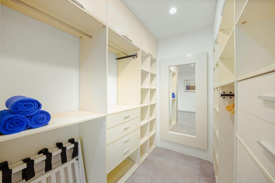Spacious walk-in closet with full-length mirror, built-in shelves, and beach towels ready.