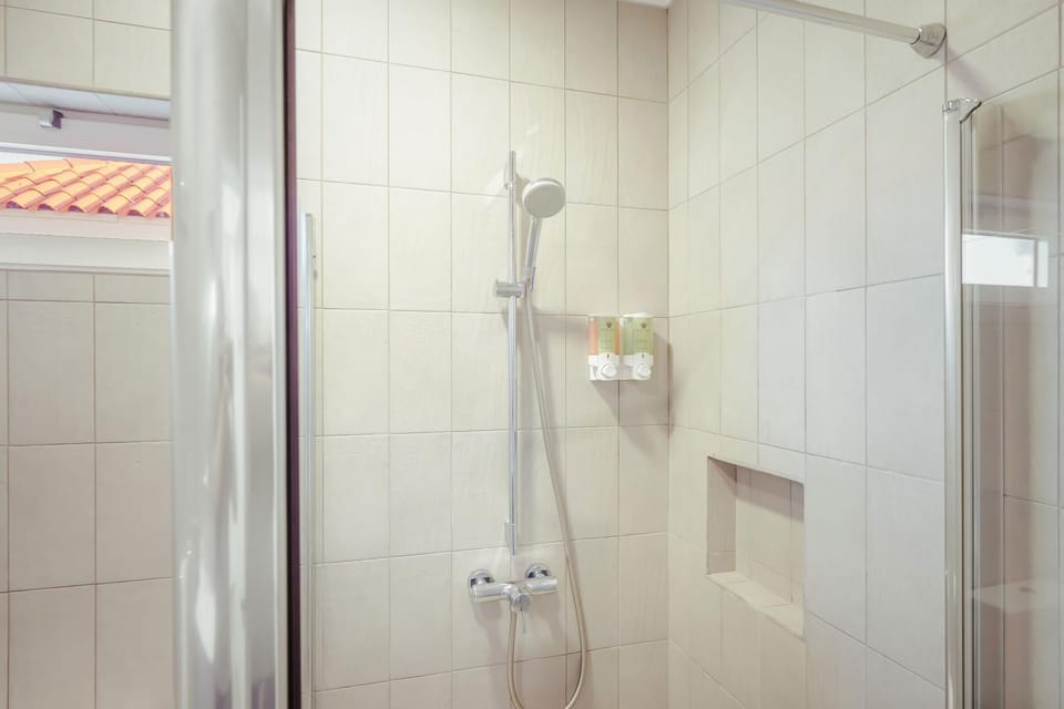 Elegant bathroom with glass shower, large mirror, and essential amenities included.