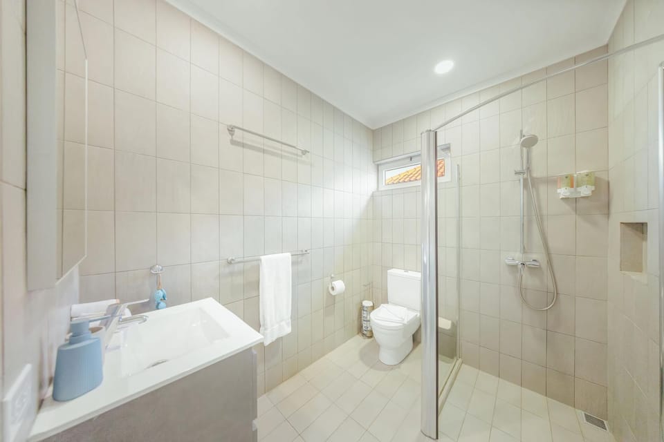 Spacious bathroom with walk-in shower, fresh towels, and Aruba Aloe toiletries provided.