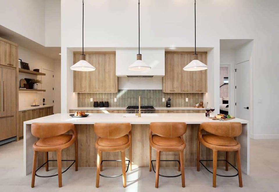 Unit 2: Fully equipped kitchen boasting high-end stainless steel appliances and a large island offering bar seating overlooking the formal dining area.