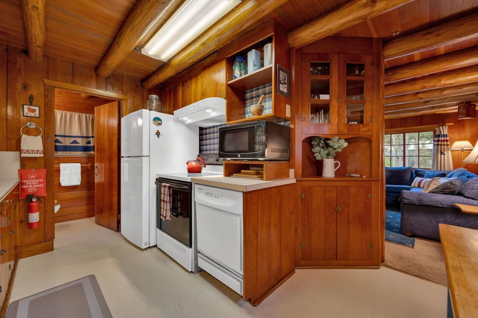 Fully equipped cooking area with stove, fridge and classic wood cabinetry.