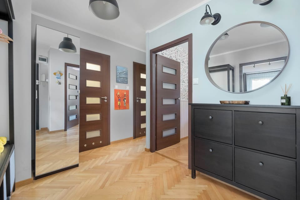A hallway with wooden flooring and large mirrors on built-in wardrobes. The space feels clean and well-organized.