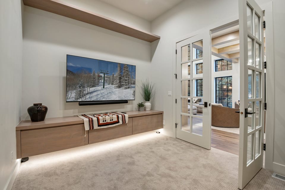 Through a set of French doors, is a beautiful family / office space with 65" smart TV