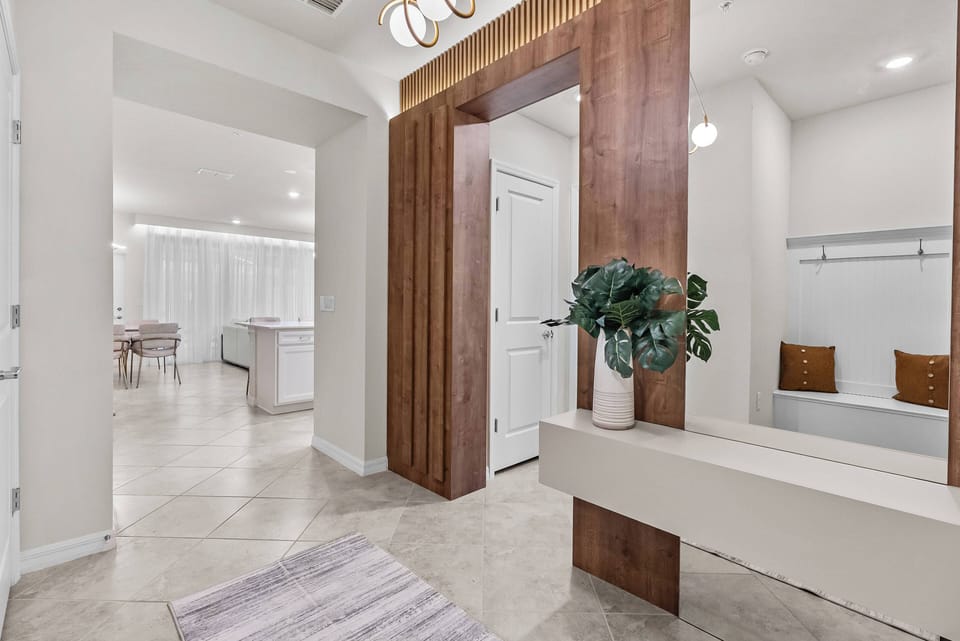 Welcome to a bright entryway with stylish wooden accents and modern finishes. The spacious design includes a comfortable bench, ideal for relaxing, as natural light gently fills the inviting space ahead. Enjoy your stay!