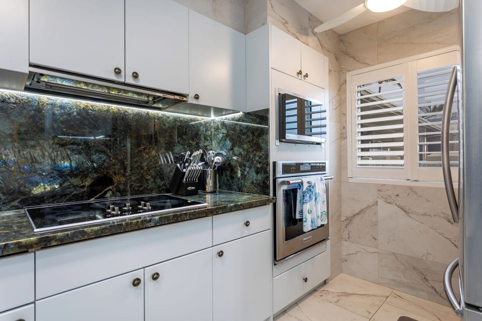 Your fully equipped kitchen features stunning marble surfaces, modern appliances, and sleek white cabinetry—perfect for preparing meals at your leisure during your stay.
