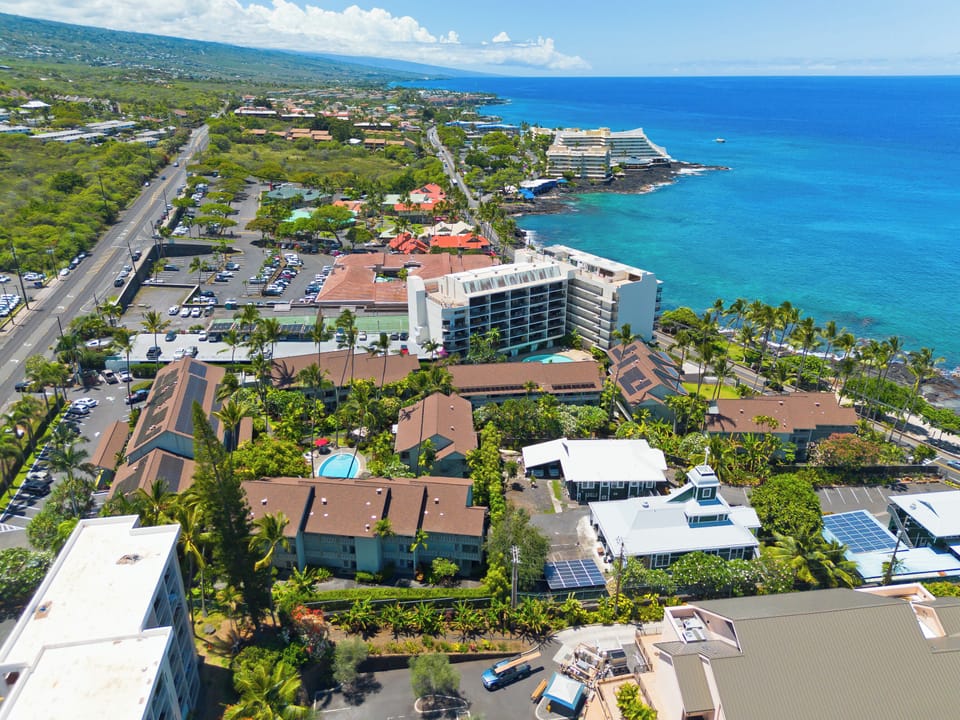 Aerial view of the coastal property surrounded by lush tropical landscaping along the scenic Hawaiian shoreline, with nearby beaches and resort area.