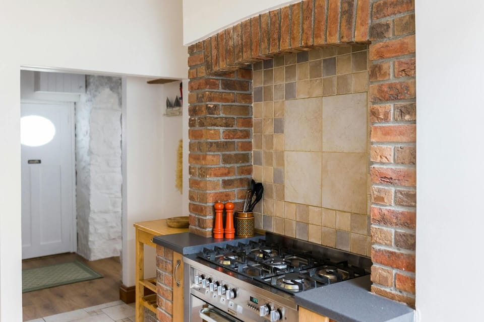 Electric oven and gas hob range set within old brick chimney breast