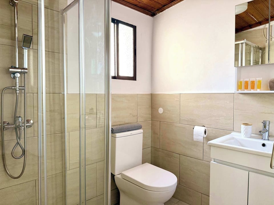 The bathroom features a luxurious waterfall shower, fresh towels, and complimentary shampoo and shower gel for your convenience.