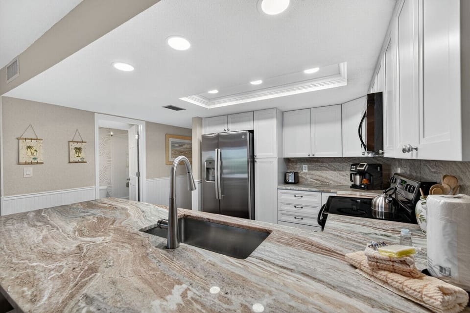 Another angle of the airy kitchen highlights generous counter space & clean, coastal-inspired finishes