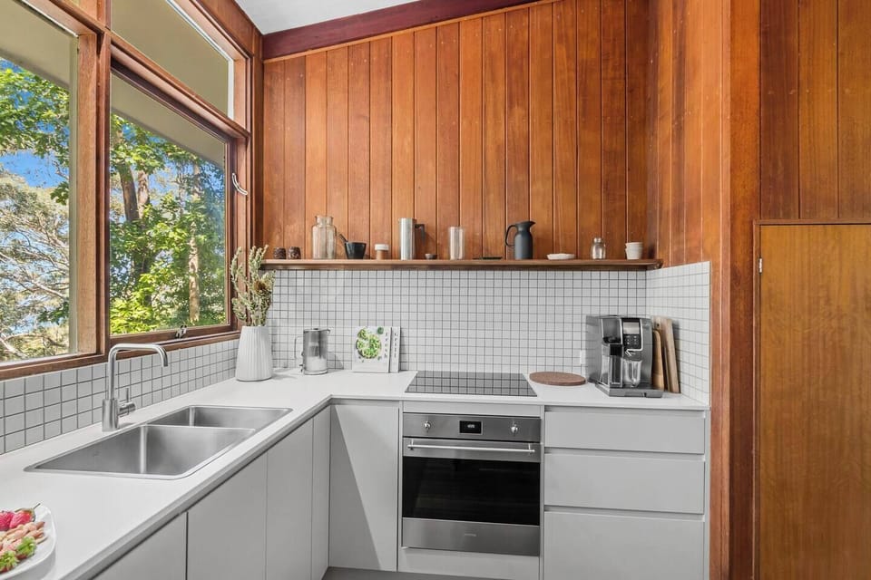 The kitchen blends timber warmth with crisp design and includes a full suite of appliances, including oven, stove and dishwasher.