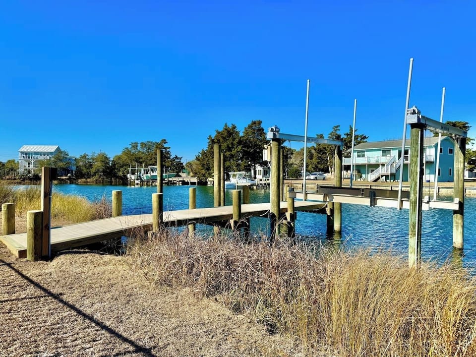 Private backyard dock with boat lift and fillet table, fenced-in backyard, fire pit with Adirondack chairs, hammocks, propane grill, picnic table, outdoor shower, expansive waterfront back deck, neighborhood boat ramp and dock