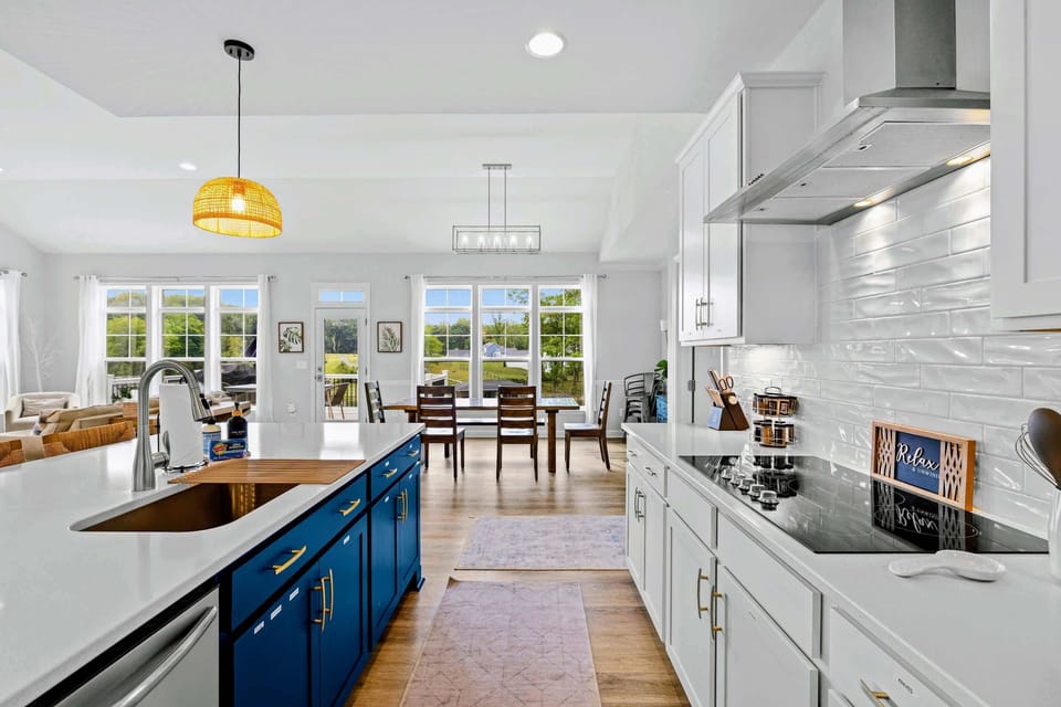 Kitchen - Undermount sink with wooden drying rack faces the dining area and a wall of windows onto the back deck.