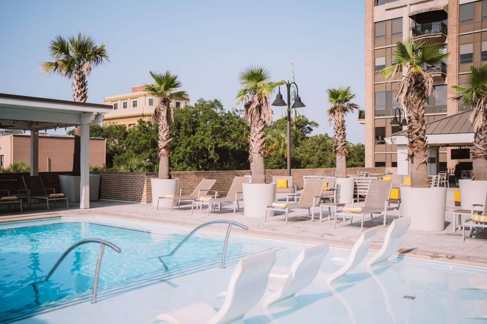 Pool deck lined with palm trees and yellow cushioned chairs