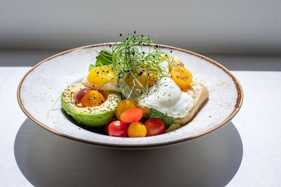 Avocado toast topped with poached eggs and cherry tomatoes