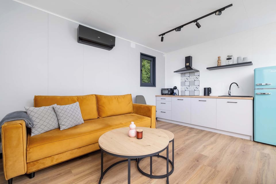 Another angle of the living room showing the full open kitchen layout. The clean, modern design is balanced by colorful accents.