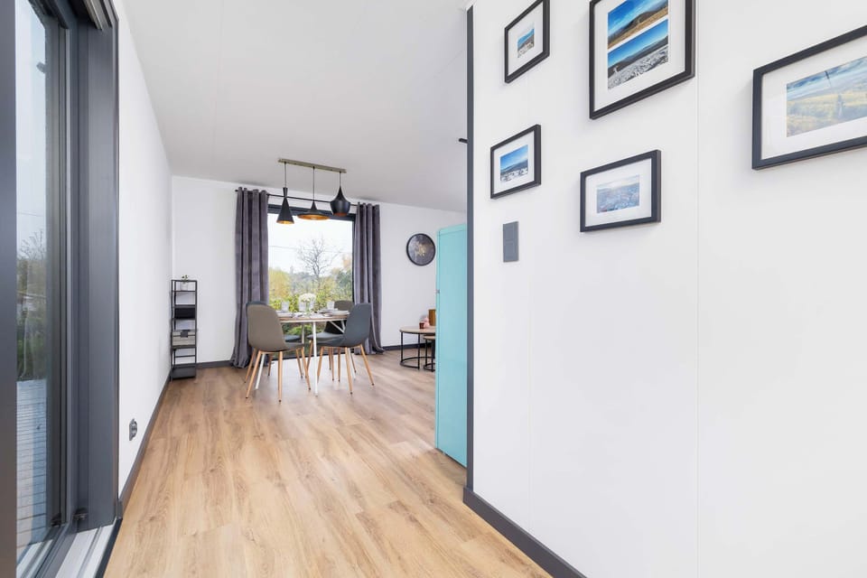 A narrow corridor with bright walls and floor-to-ceiling glass doors. The layout feels spacious despite the compact space.