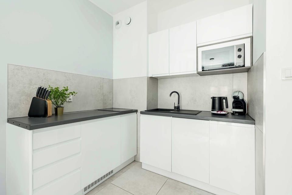 Stylish modern kitchen with sleek white cabinets, gray countertops, and built-in appliances for a clean and functional design.