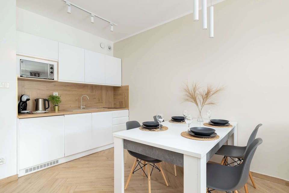 Modern kitchenette equipped with essential appliances, a coffee maker, and stylish wooden finishes.