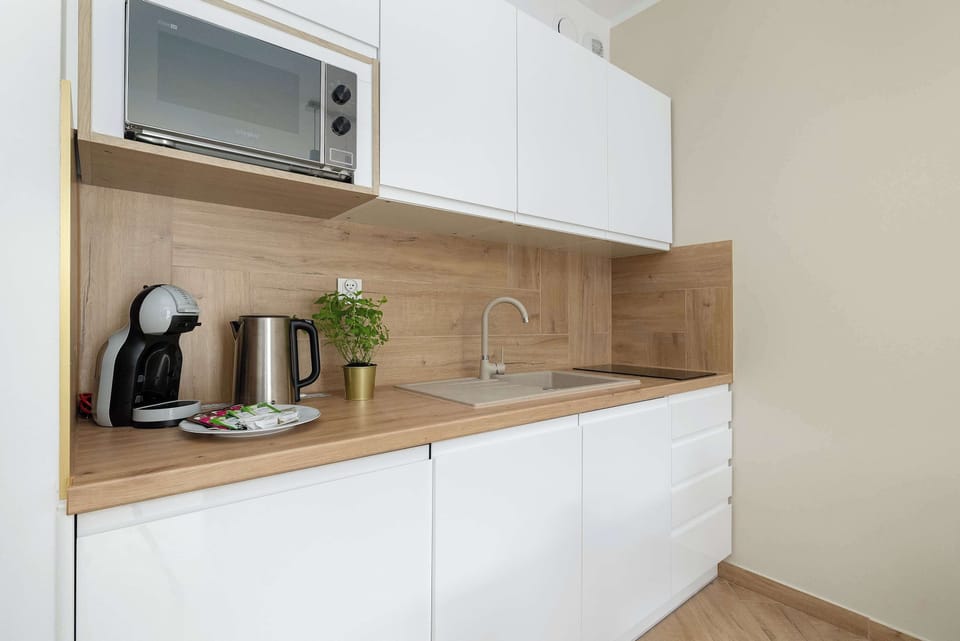 Modern kitchenette equipped with essential appliances, a coffee maker, and stylish wooden finishes.