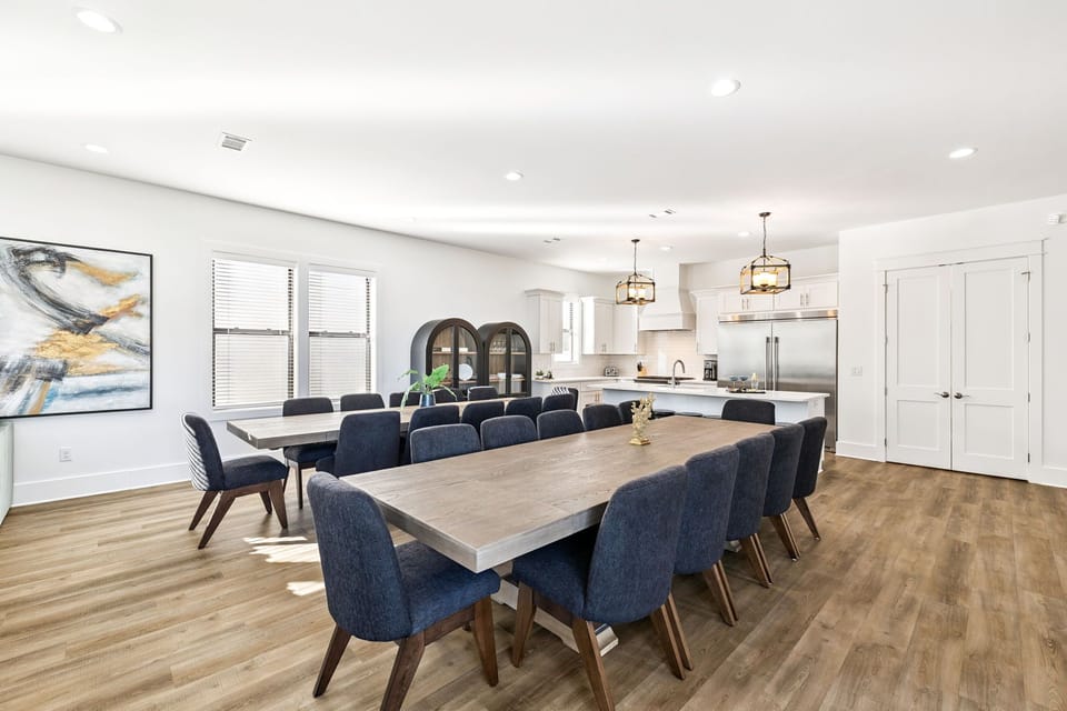 The spacious dining area flows seamlessly into a gourmet kitchen, perfect for memorable group meals and conversations around the elegant wood table.