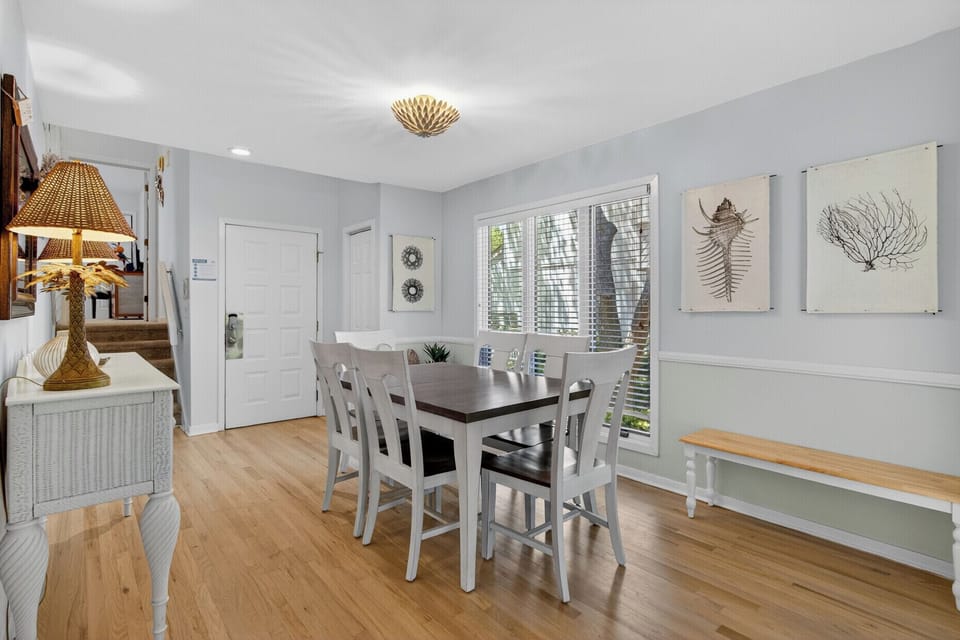 You'll love gathering around this charming dining table, where warm wood floors and coastal artwork create the perfect atmosphere for memorable meals together.