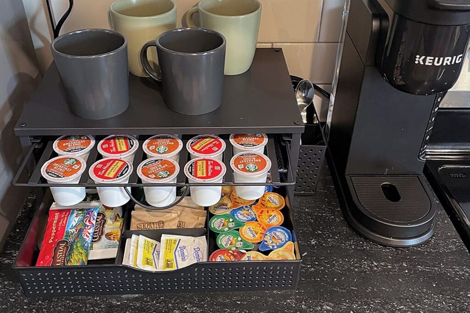 Keurig coffee station with pods, tea, sugar, and mugs ready anytime.