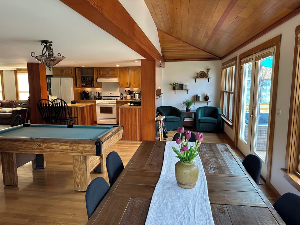 Sun filled dining area w/ dinner table, kitchen, pool table and reading nook.  