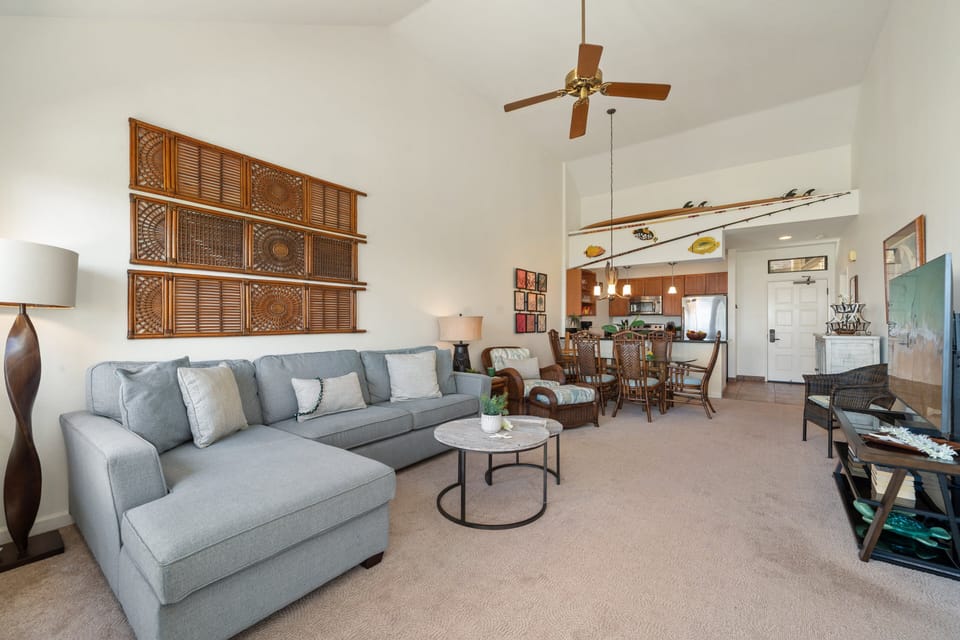 Relax in a spacious living area featuring plush seating, high ceilings, and island-inspired décor for a welcoming retreat