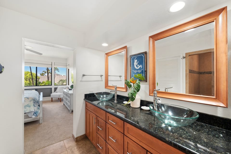 Refresh in a spacious bathroom featuring dual sinks, granite countertops, and warm wood cabinetry for a touch of luxury