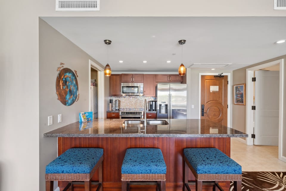 Cook in a sleek kitchen featuring a granite island and stainless steel appliances.
