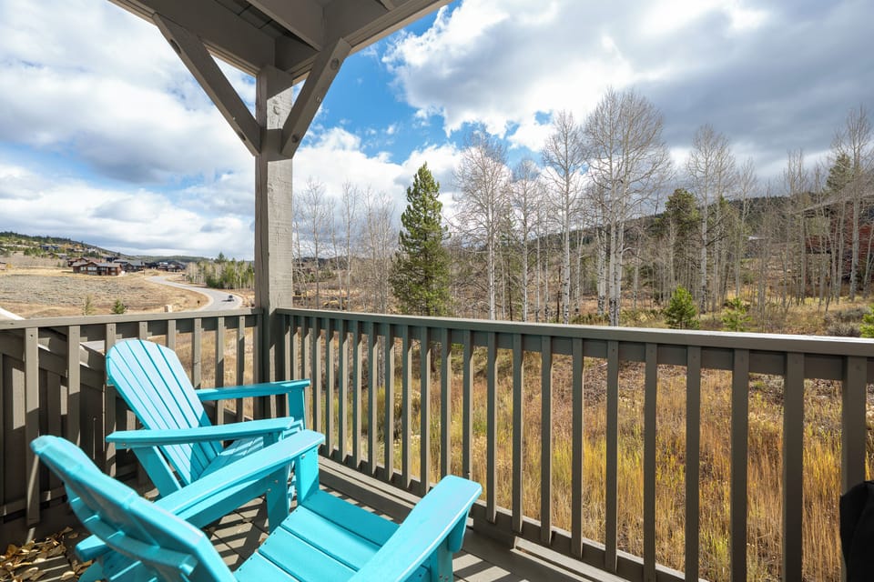 Relax on your private balcony with turquoise Adirondack chairs and sweeping mountain views—your perfect retreat spot when you stay at Kicking Horse Buckskin 3-205.