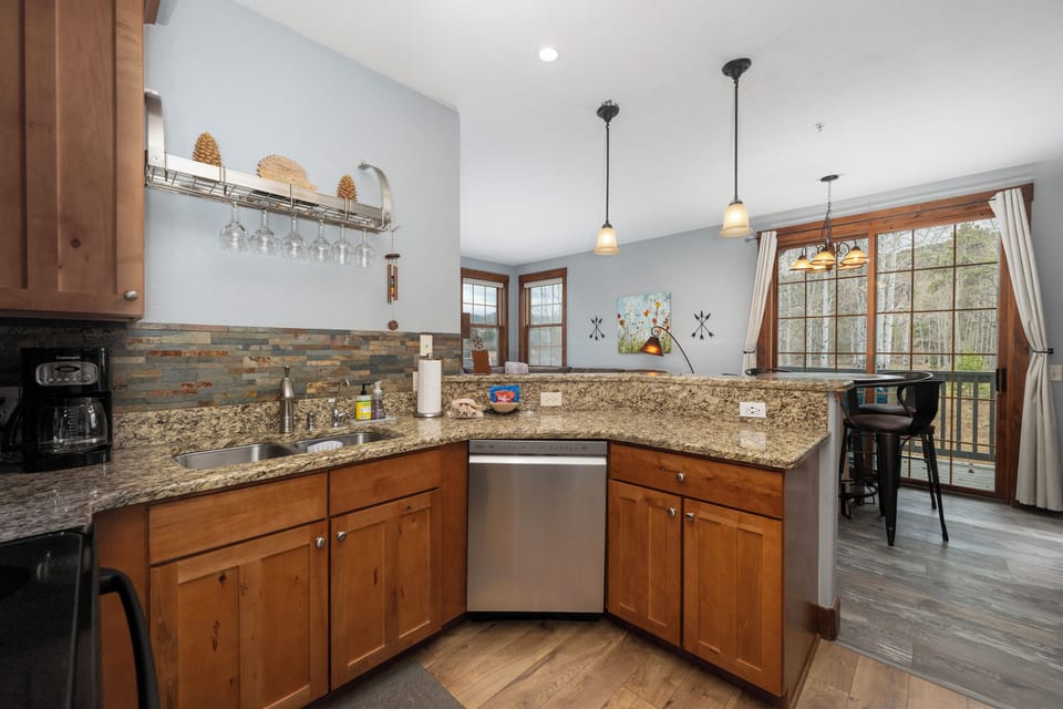 Your fully-equipped kitchen at Kicking Horse Buckskin 3-205 features granite counters, modern appliances, and warm wood accents perfect for preparing memorable meals during your stay.