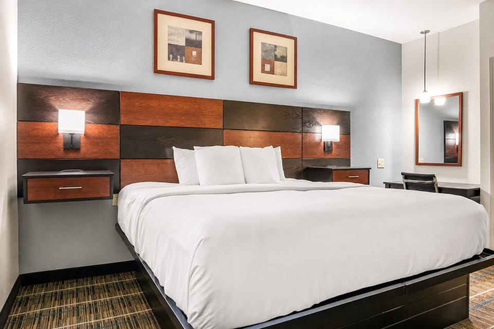 Unwind in a crisp king bed with warm bedside glow.