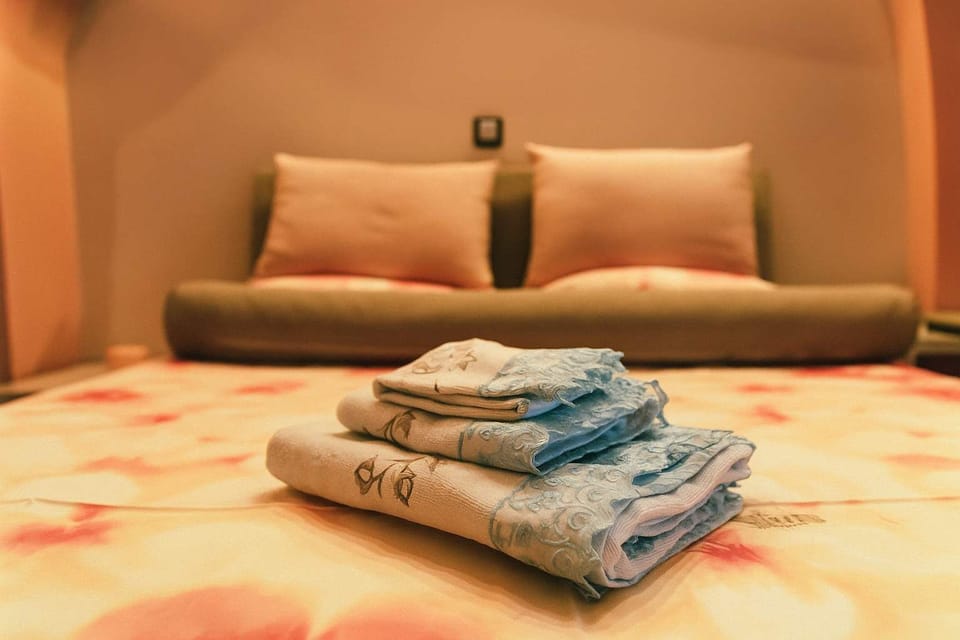 Inviting Double Bedroom with Fresh Linens
A neatly arranged double bed with plush pillows and fresh towels ready for guests — offering comfort and a welcoming touch.