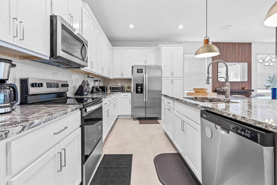 Enjoy a bright kitchen with sleek white cabinetry and stunning granite countertops that spark your culinary creativity. Modern stainless steel appliances and warm pendant lighting create a welcoming space for gatherings.