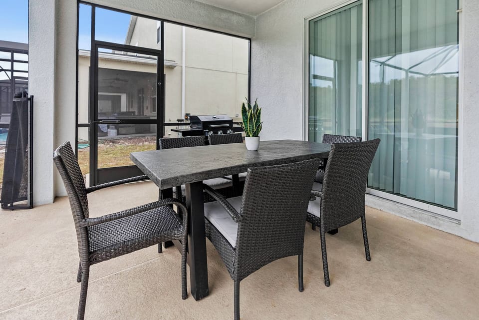 Step outside to savor al fresco dining at a sleek table with stylish wicker chairs. The sliding glass doors invite natural light, blending indoor and outdoor living, while greenery enhances this charming space.