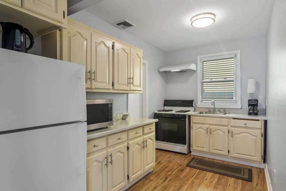 Bright, functional kitchen—fully equipped with a gas range, microwave, coffee maker, electric kettle, and full-size fridge for easy home-cooked meals.