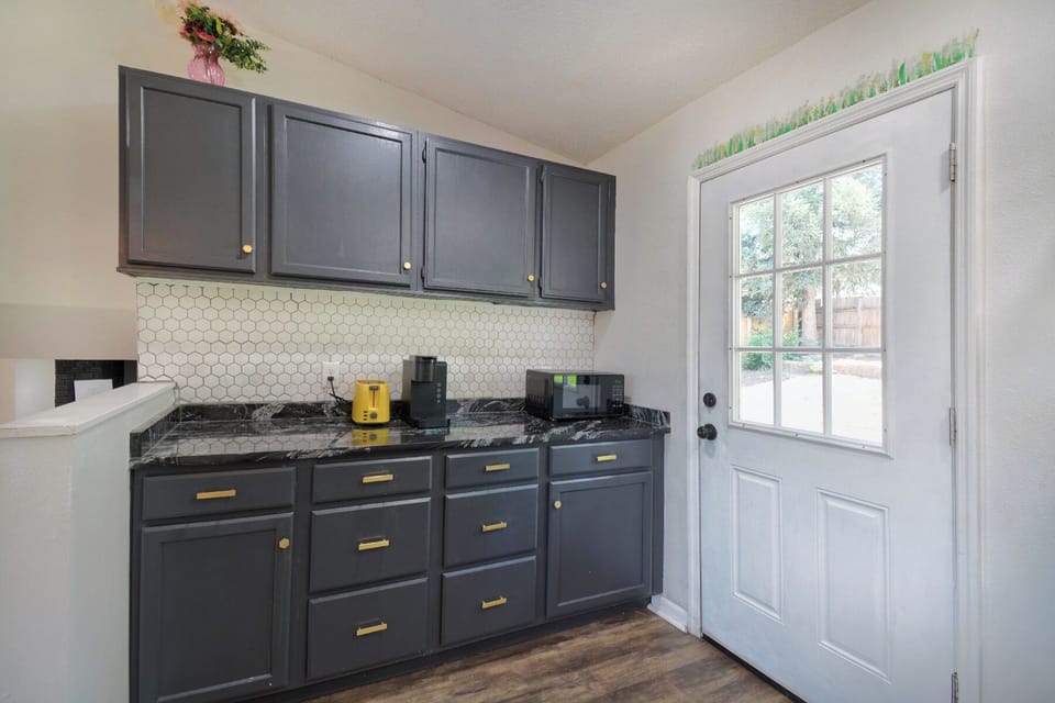 Your stylish kitchen awaits with sleek navy cabinets, gleaming granite countertops, and warm wood floors. Natural light pours through the glass door while you prepare meals in this thoughtfully designed space.