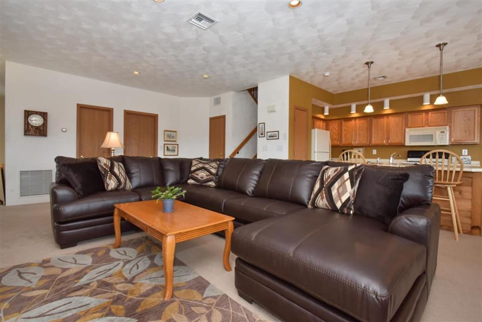 Bright lounge with leather seating, coffee table, and direct access to kitchen and dining space.