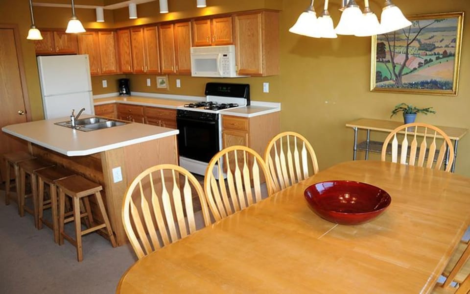 Open kitchen with breakfast bar and adjoining dining area, ideal for group meals.