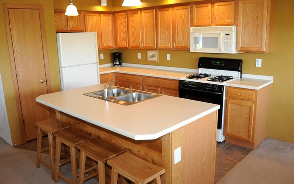 Fully equipped kitchen with wood cabinetry, appliances, and central island with bar seating.