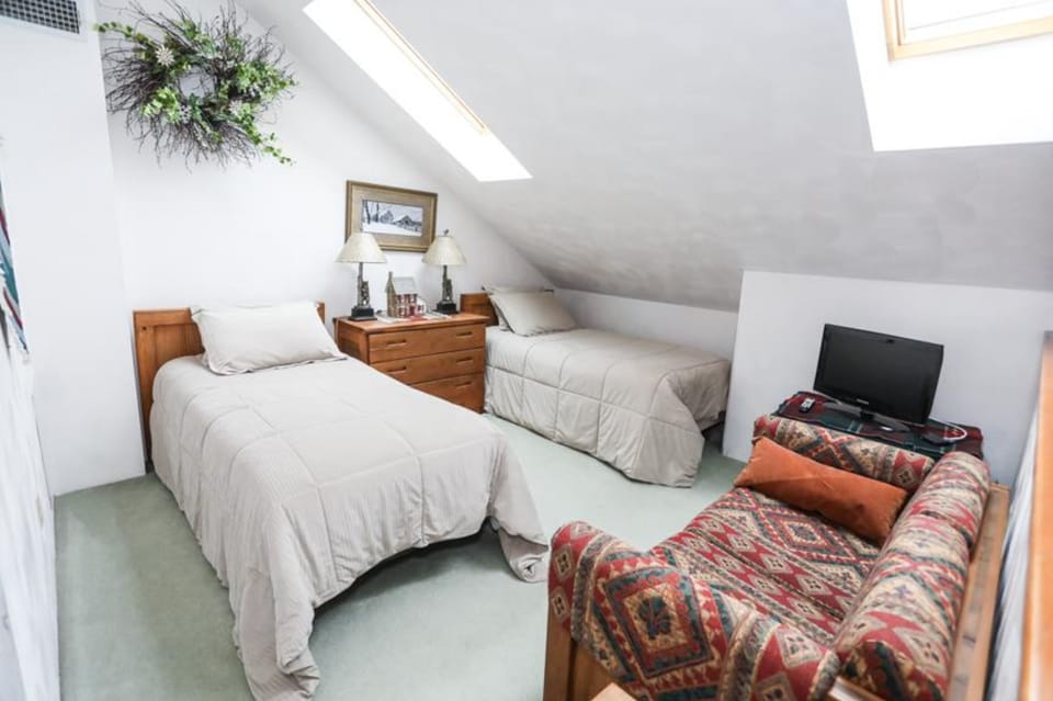 Bright loft bedroom with two twin beds and its own full bathroom, ideal for kids or extra guests.